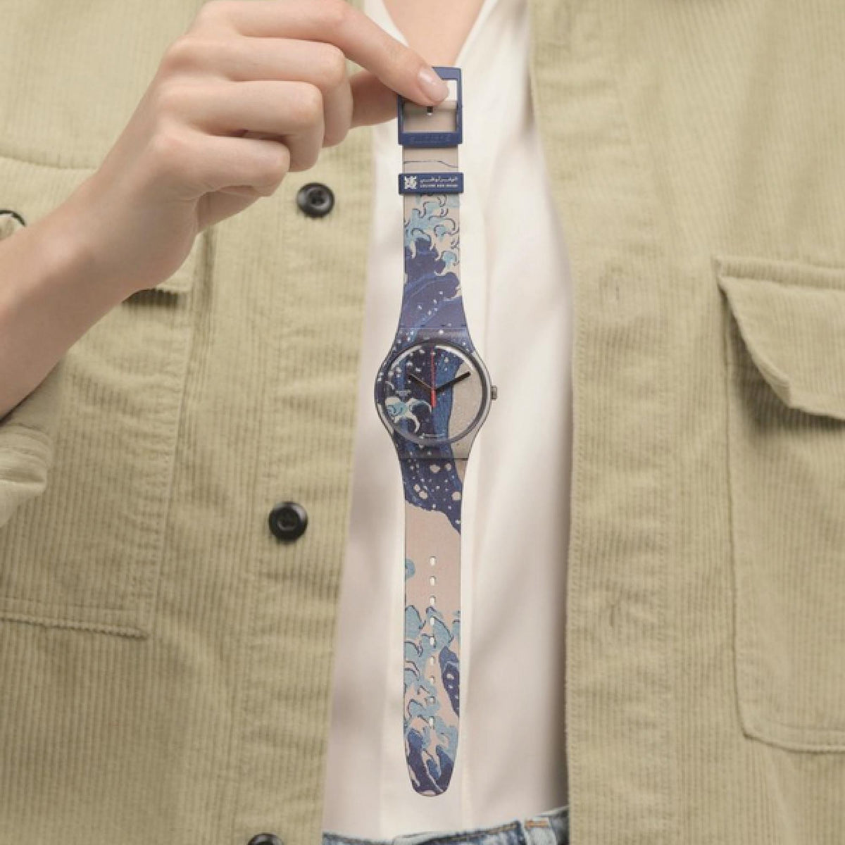 Hand wearing quartz watch with blue art strap and round dial with red second hand