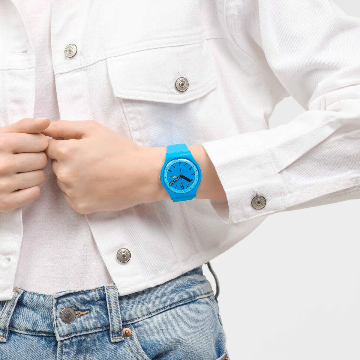 Blue quartz wristwatch on wrist with blue dial and black hands under a white shirt cuff.