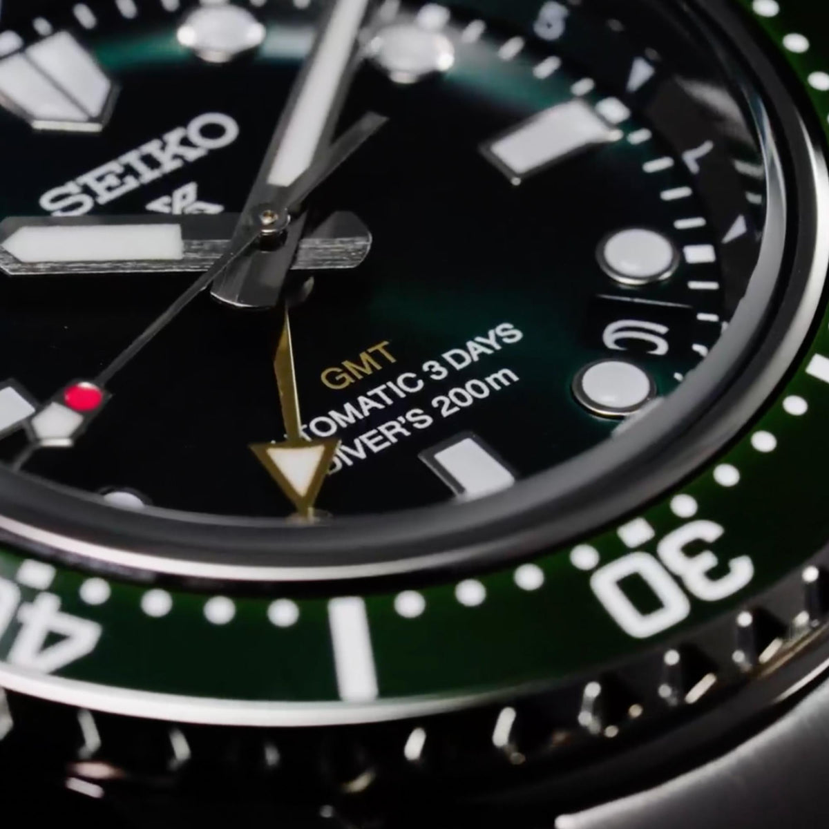 Close-up of Seiko GMT diver watch dial with green bezel and gold GMT hand
