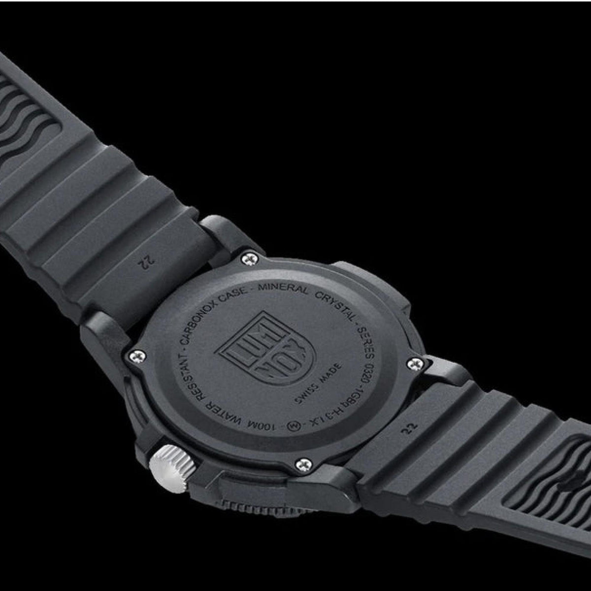 Black watch caseback with embossed text and screws, on black rubber strap