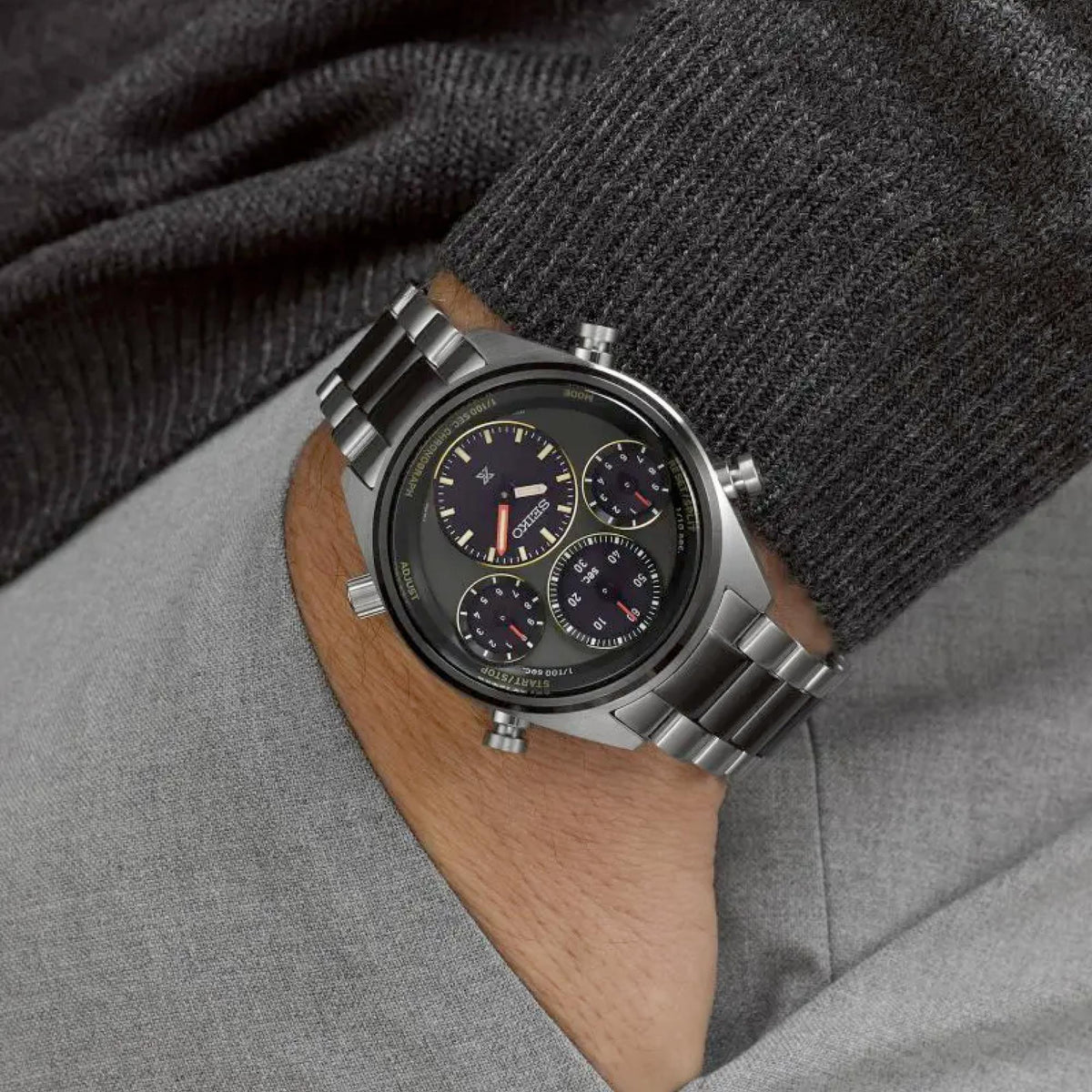 Chronograph watch worn on wrist with dark khaki dial and stainless steel linked bracelet