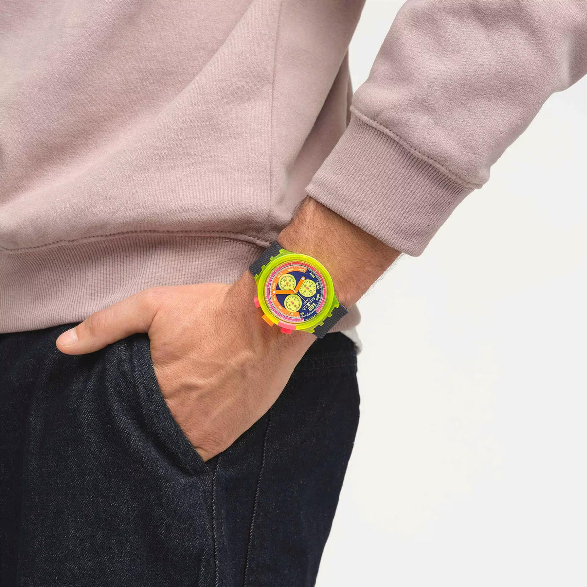 Swatch neon watch on wrist with black textured strap and bright multicolor dial.