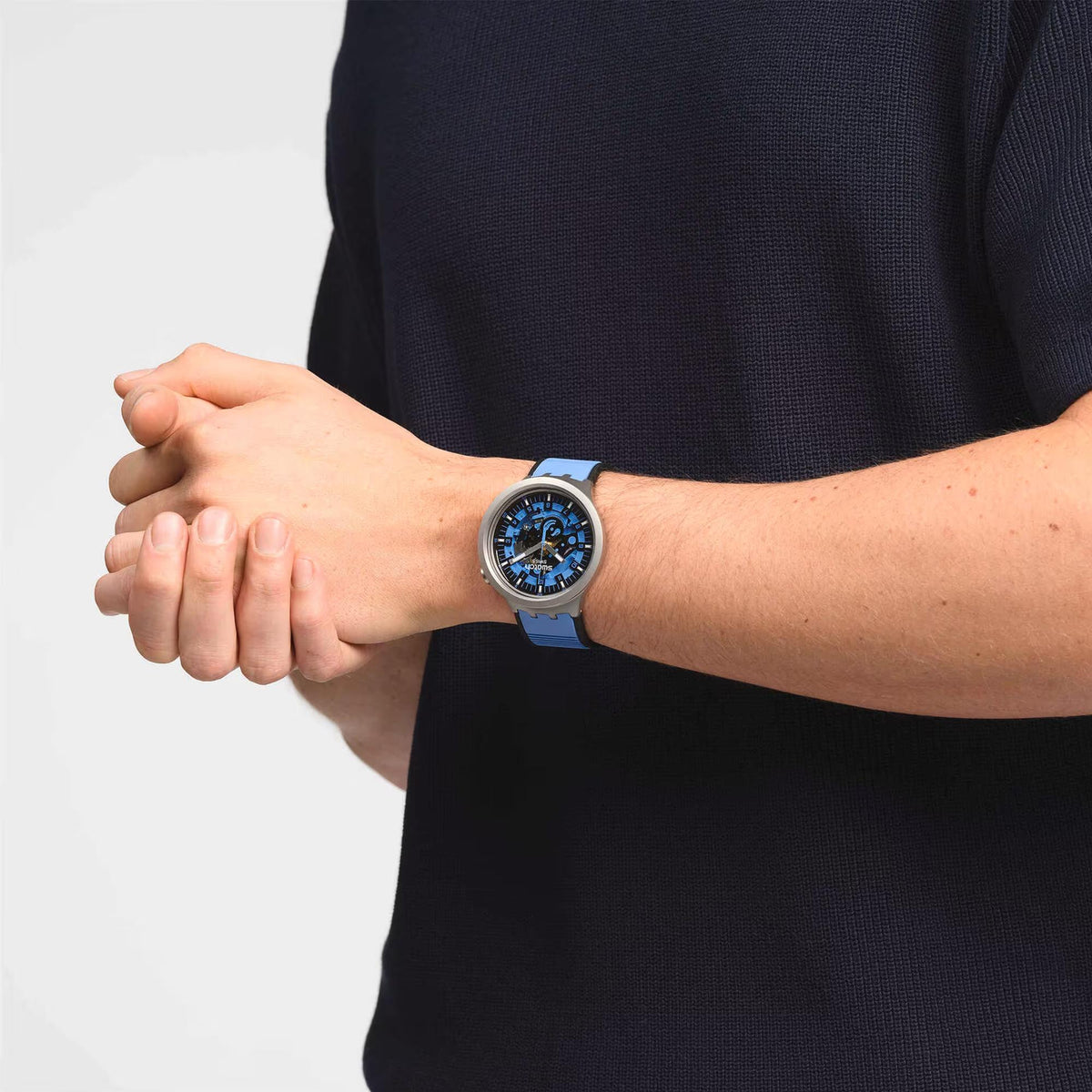 Swatch blue quartz watch on wrist wearing blue rubber strap with blue face