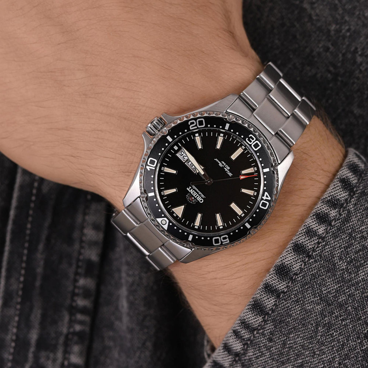 Men's steel automatic watch worn on wrist with black dial and date window