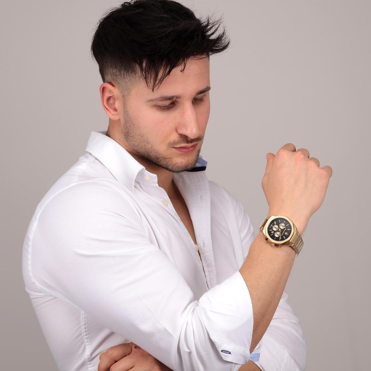 Gold-tone chronograph watch on wrist with black dial and linked bracelet
