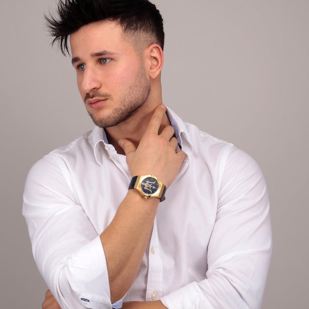 Men's Maserati watch on wrist with blue leather strap and blue dial, gold case.