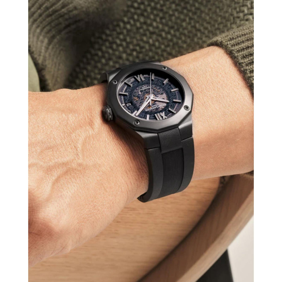 Men's black rubber watch on wrist, dark dial with Roman numerals and openwork hands