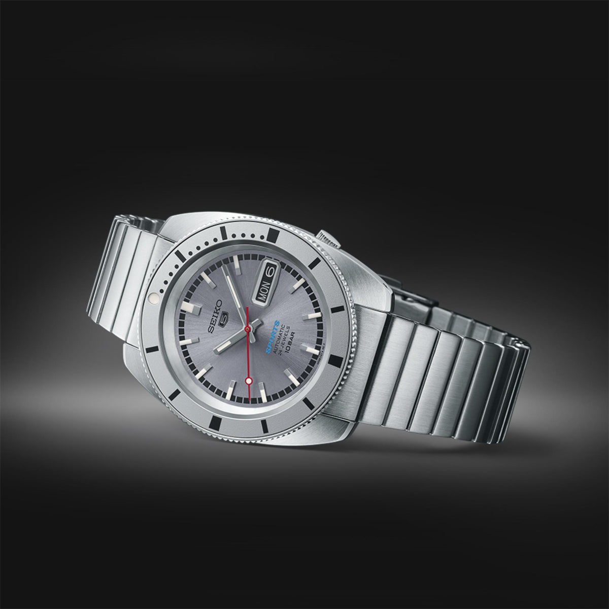 Men's stainless steel watch angled view with gray dial, red seconds hand, ribbed bezel.