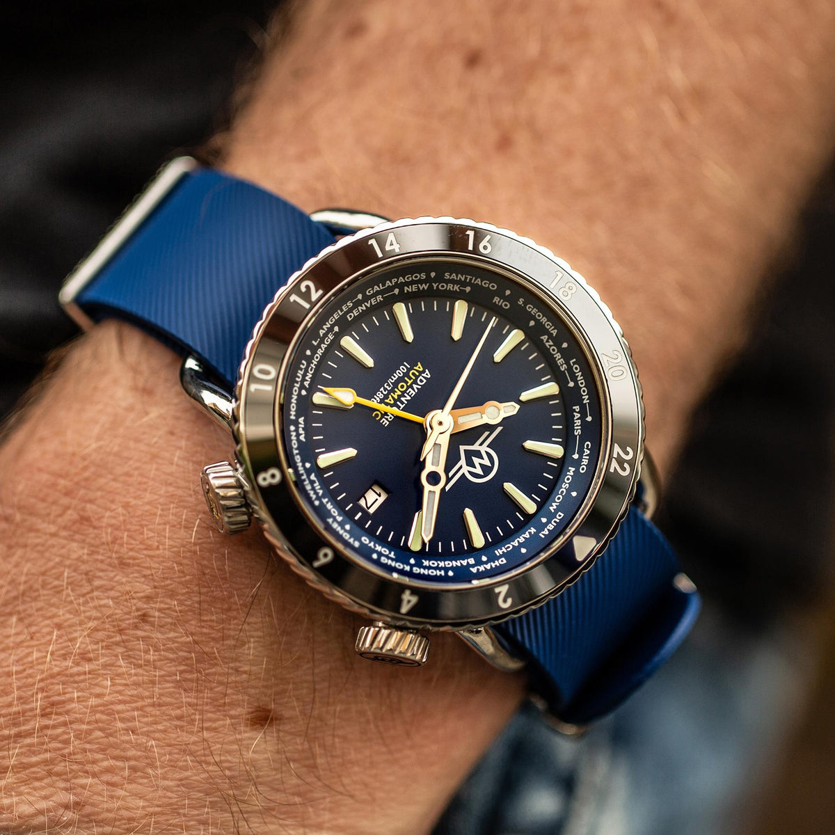 Men's automatic watch on wrist with blue dial and blue strap, crown visible