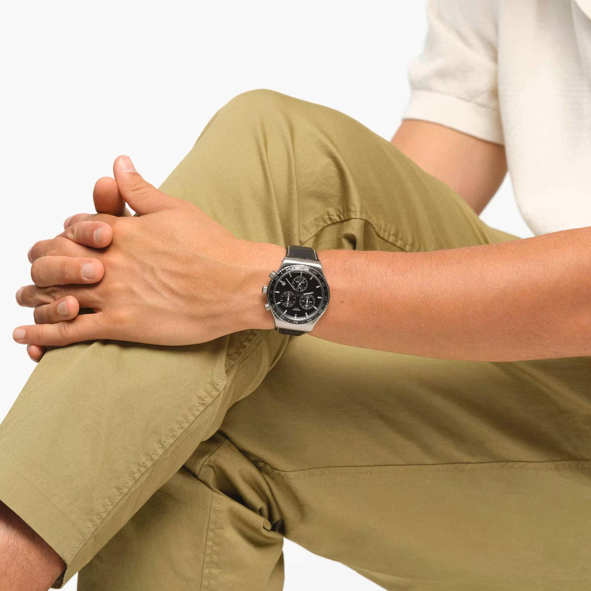 Swatch chronograph watch with black dial and black leather strap on wrist