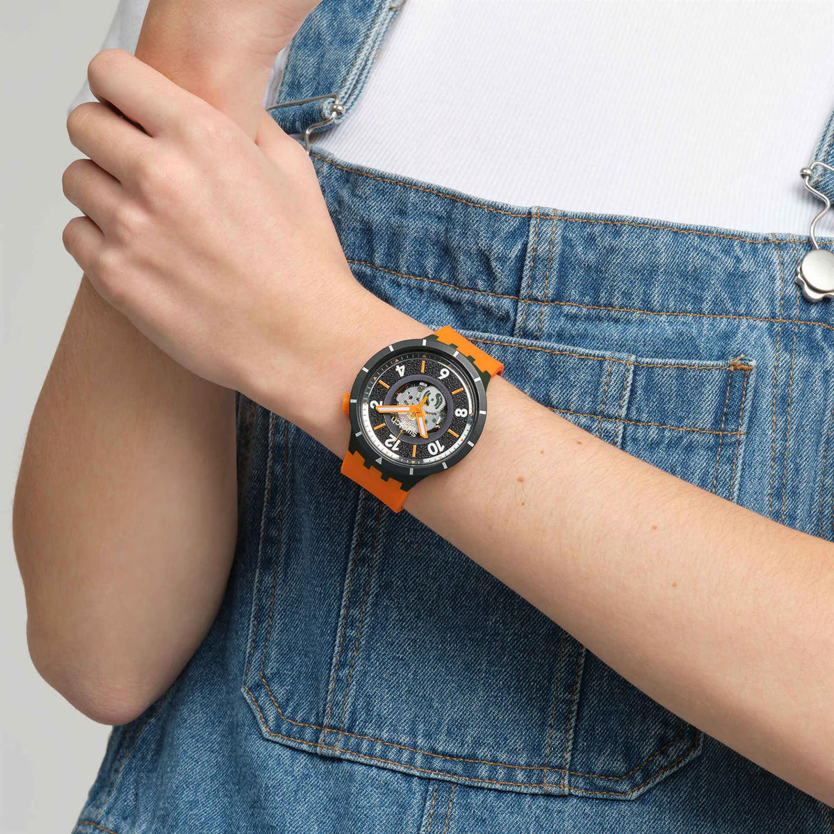 Silicone strap watch with black dial and orange bezel, worn on wrist