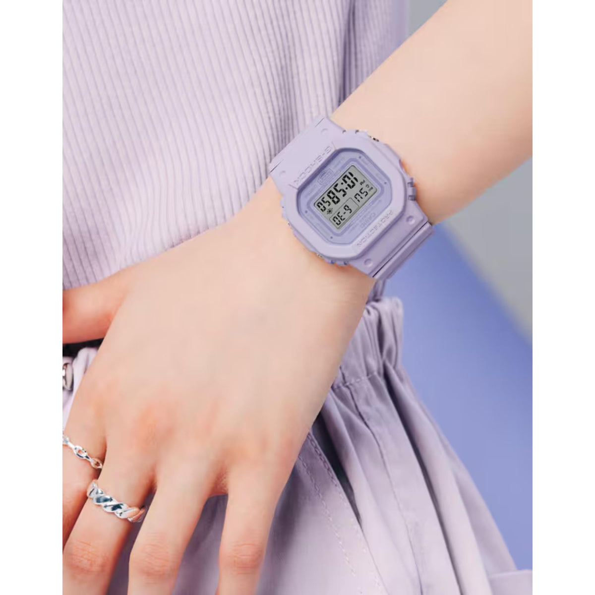 Lilac Casio G-Shock digital wristwatch on wrist with square LCD and resin strap