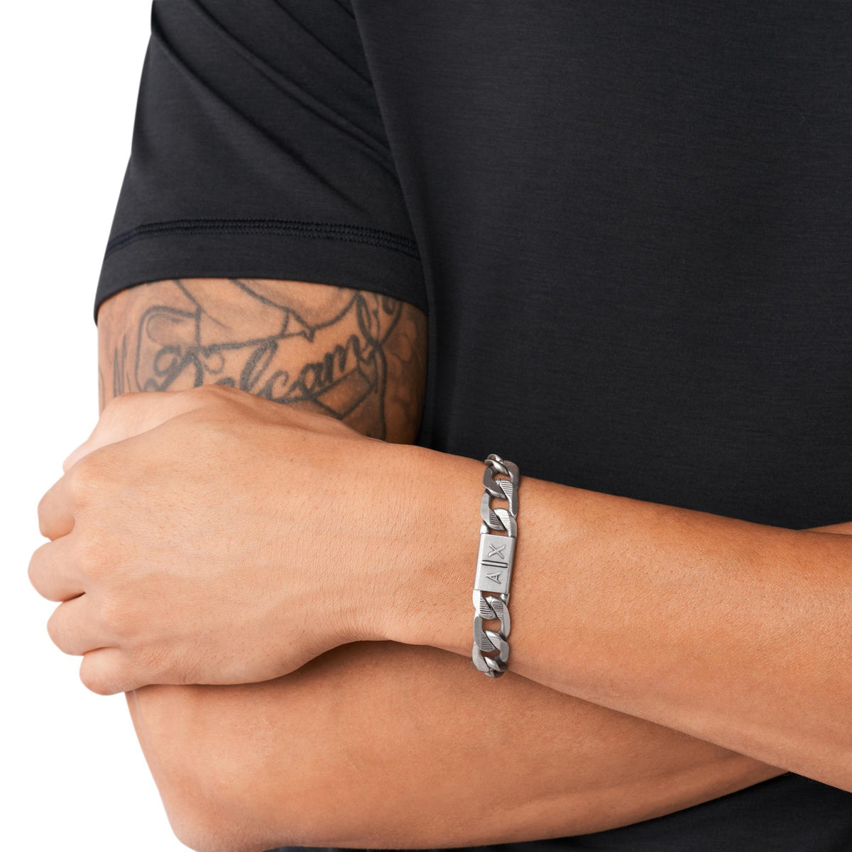 Stainless steel chain bracelet on forearm with engraved AX logo plate