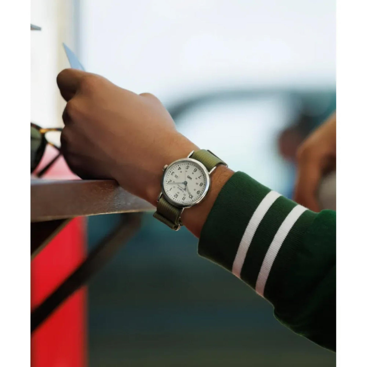 Wrist-worn quartz watch with white dial and green fabric strap on forearm