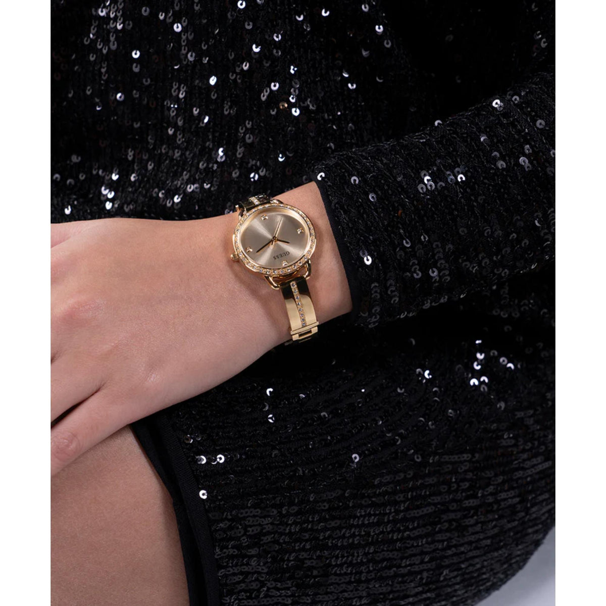 Gold tone analog wristwatch on wrist, champagne dial with crystal bezel