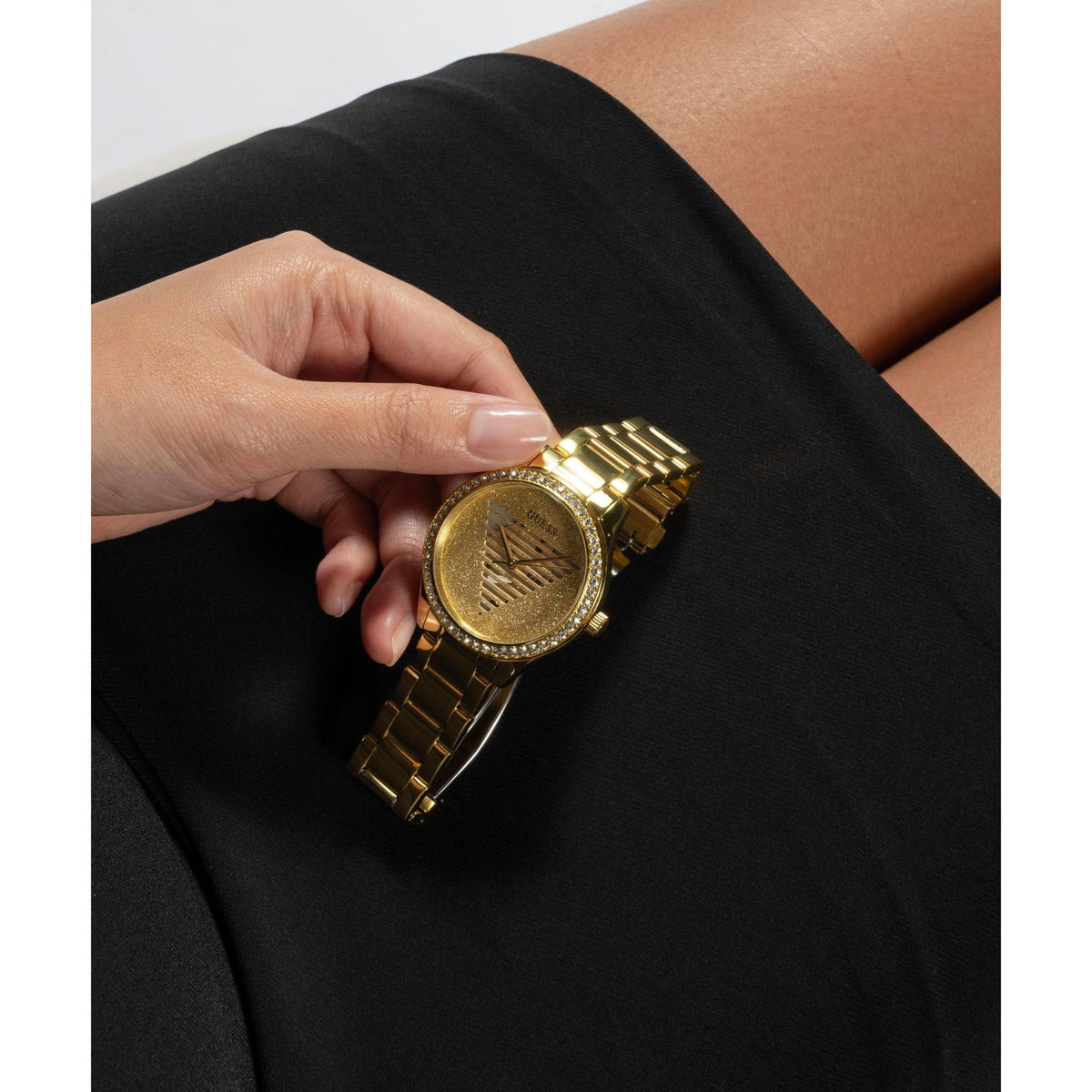 Gold tone analog watch with champagne dial and rhinestone bezel on wrist, link bracelet