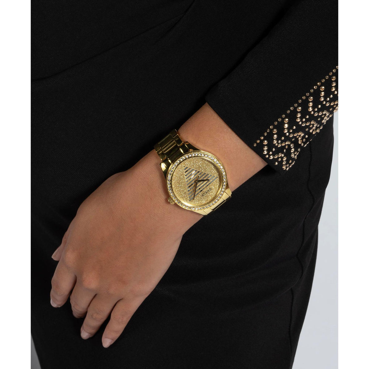 Gold tone analog ladies watch with champagne dial and rhinestone bezel on wrist