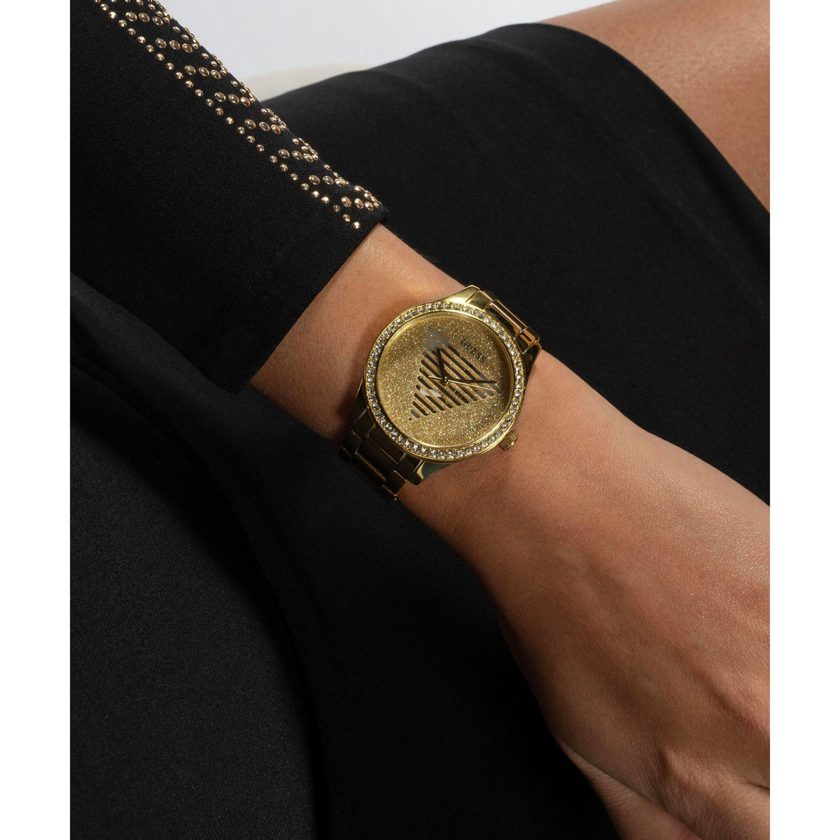 Gold tone analog ladies watch with champagne dial and rhinestone bezel on wrist sleeve