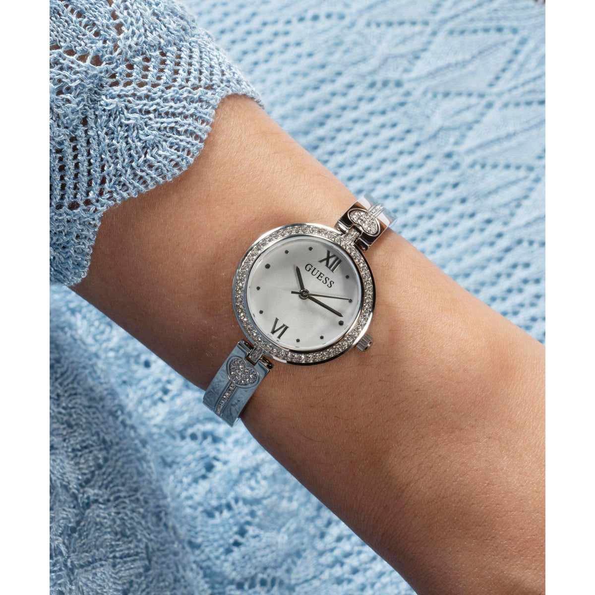 Silver-tone analog watch with white dial and Roman numerals, bracelet on wrist