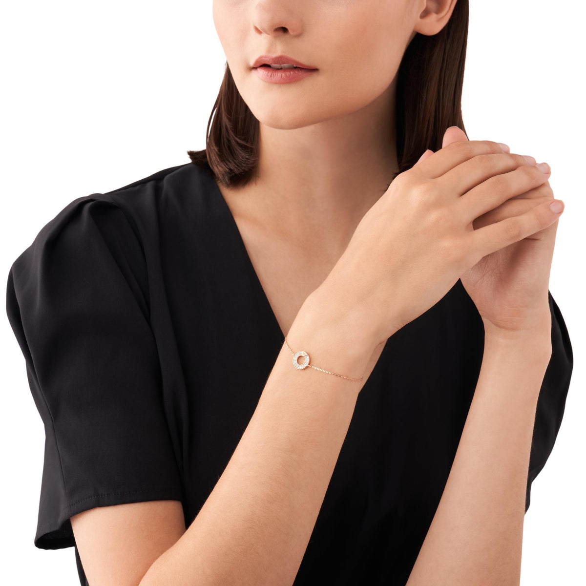 Rose gold-tone bracelet worn on wrist, featuring round logo charm and oval ring centerpiece with stones
