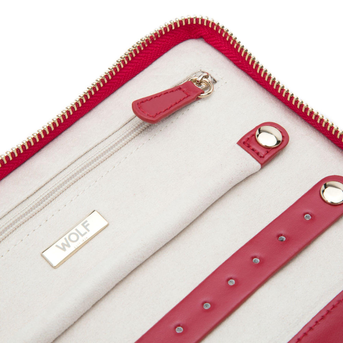 Close-up of red interior jewelry portfolio with beige lining, zipper, and stud strap loops.