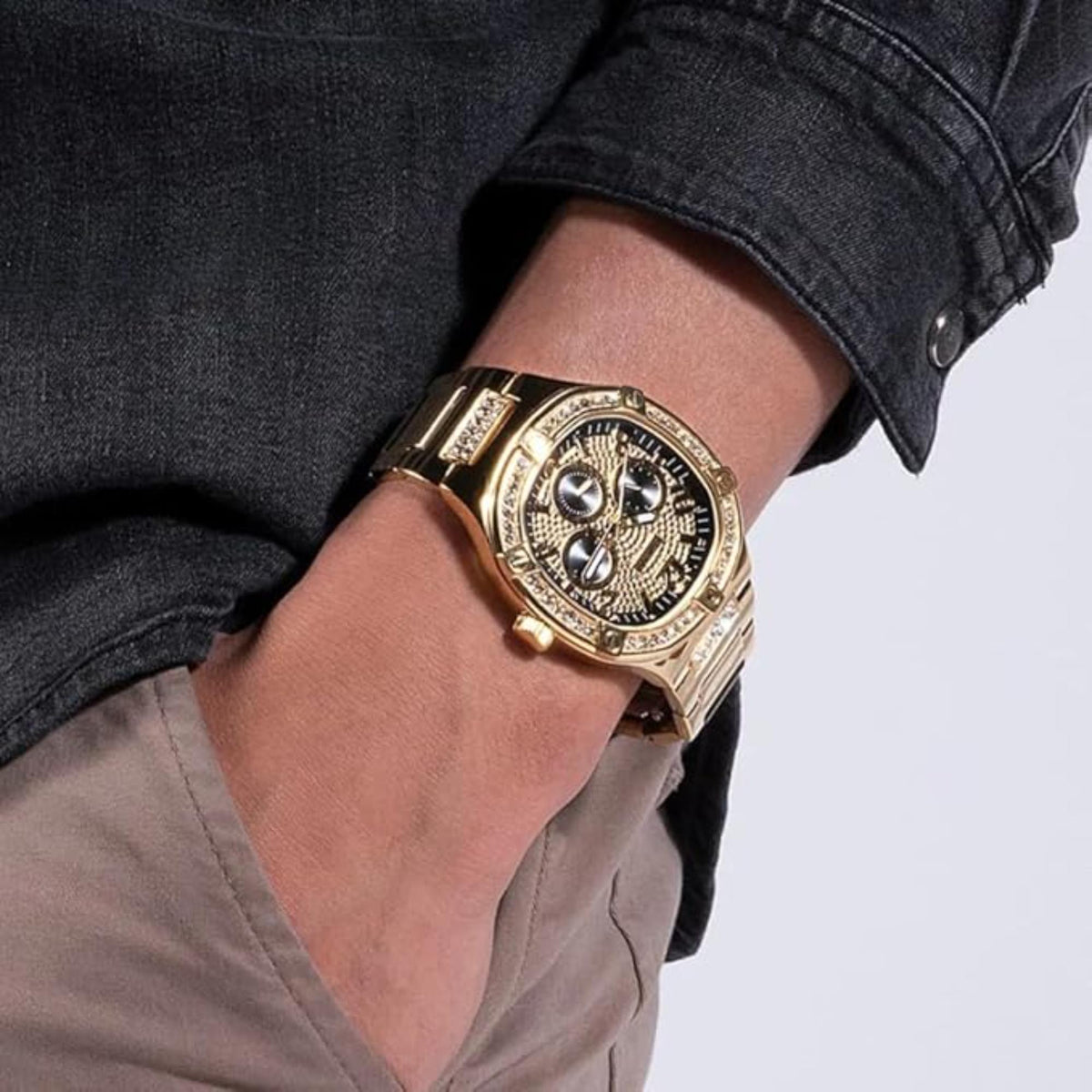 Gold-tone watch on wrist with black dial and crystal-encrusted bezel.
