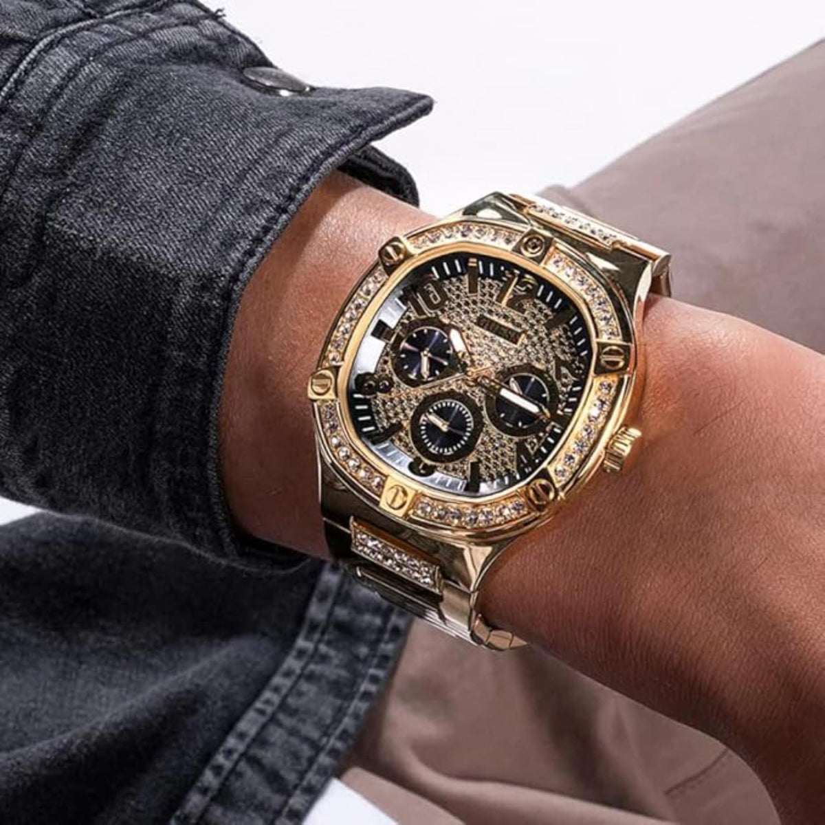 Gold-tone chronograph-style watch with black dial, crystal bezel, and subdials.
