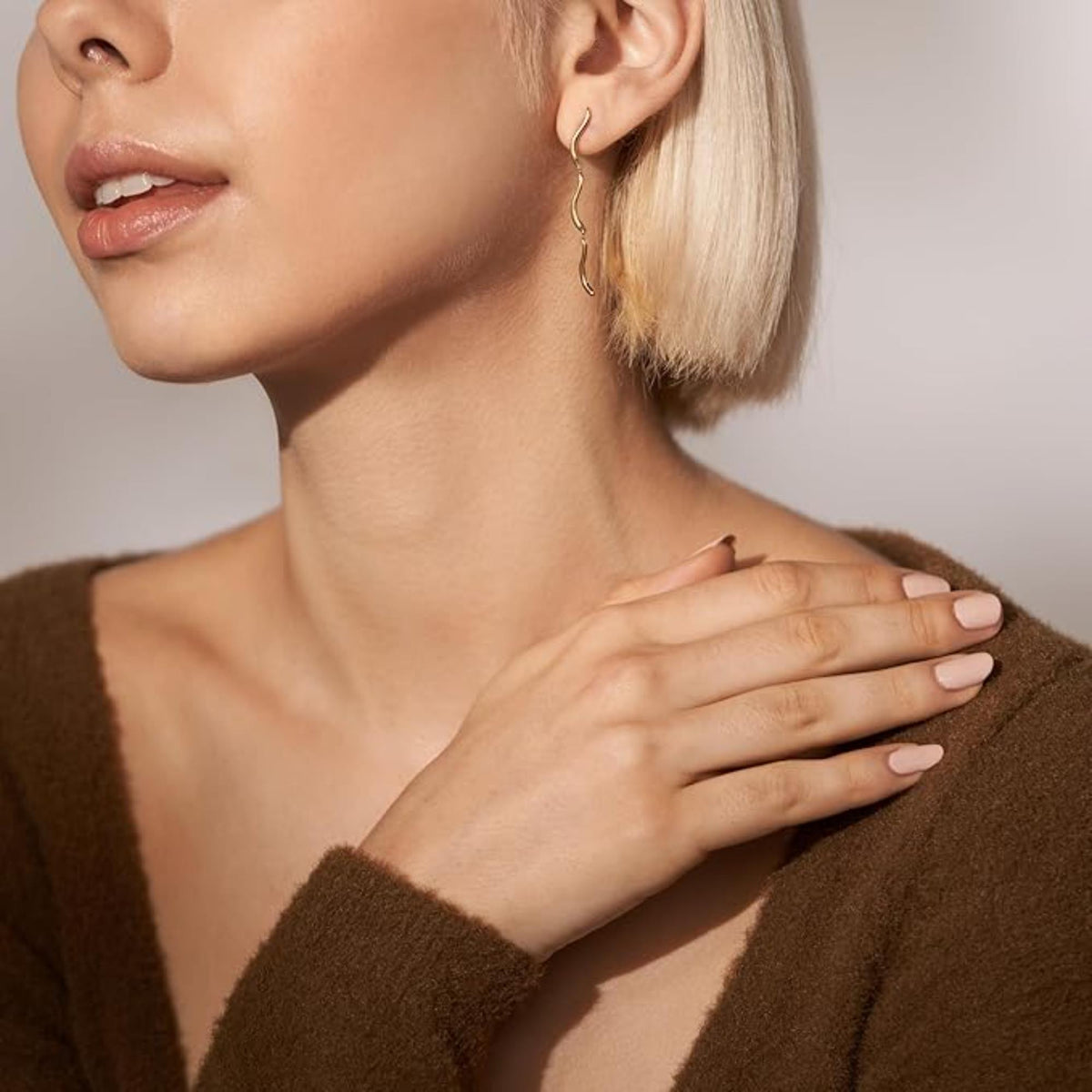 Gold-tone wave drop earrings on model, long curved wavy bar dangles