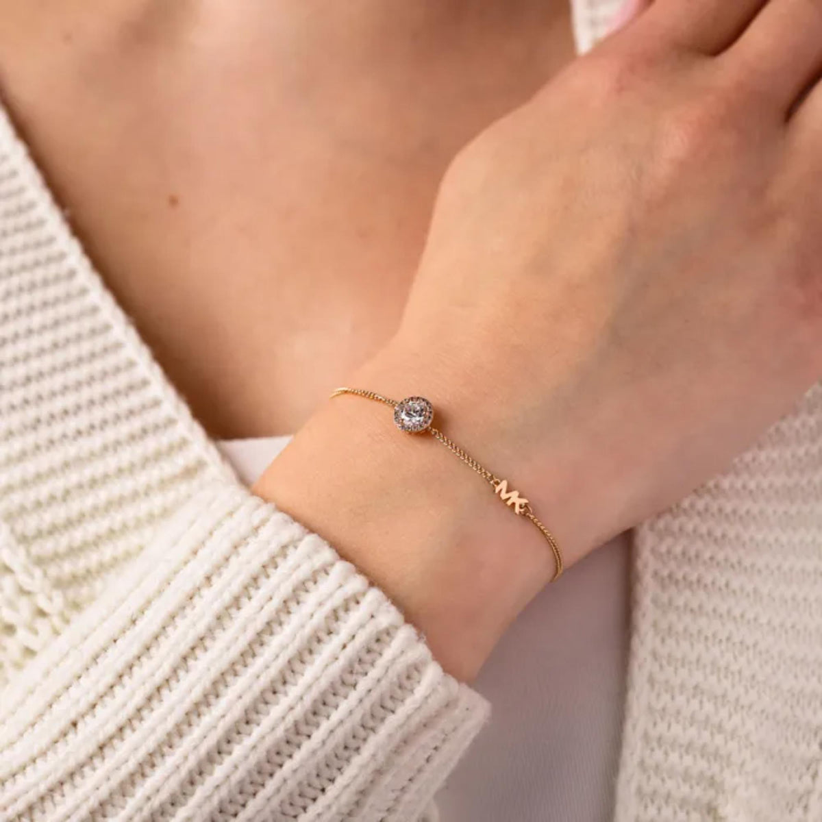 Gold-toned halo slider bracelet worn on wrist with small round crystal and M charm