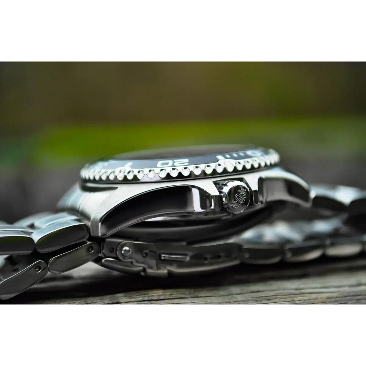 Stainless steel watch with crown and ridged bezel detail, black dial