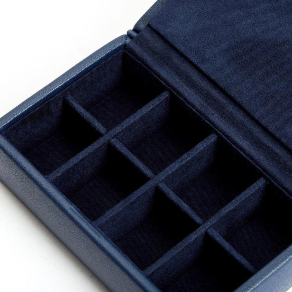 Close-up of open navy cufflink box interior showing multiple square slots.