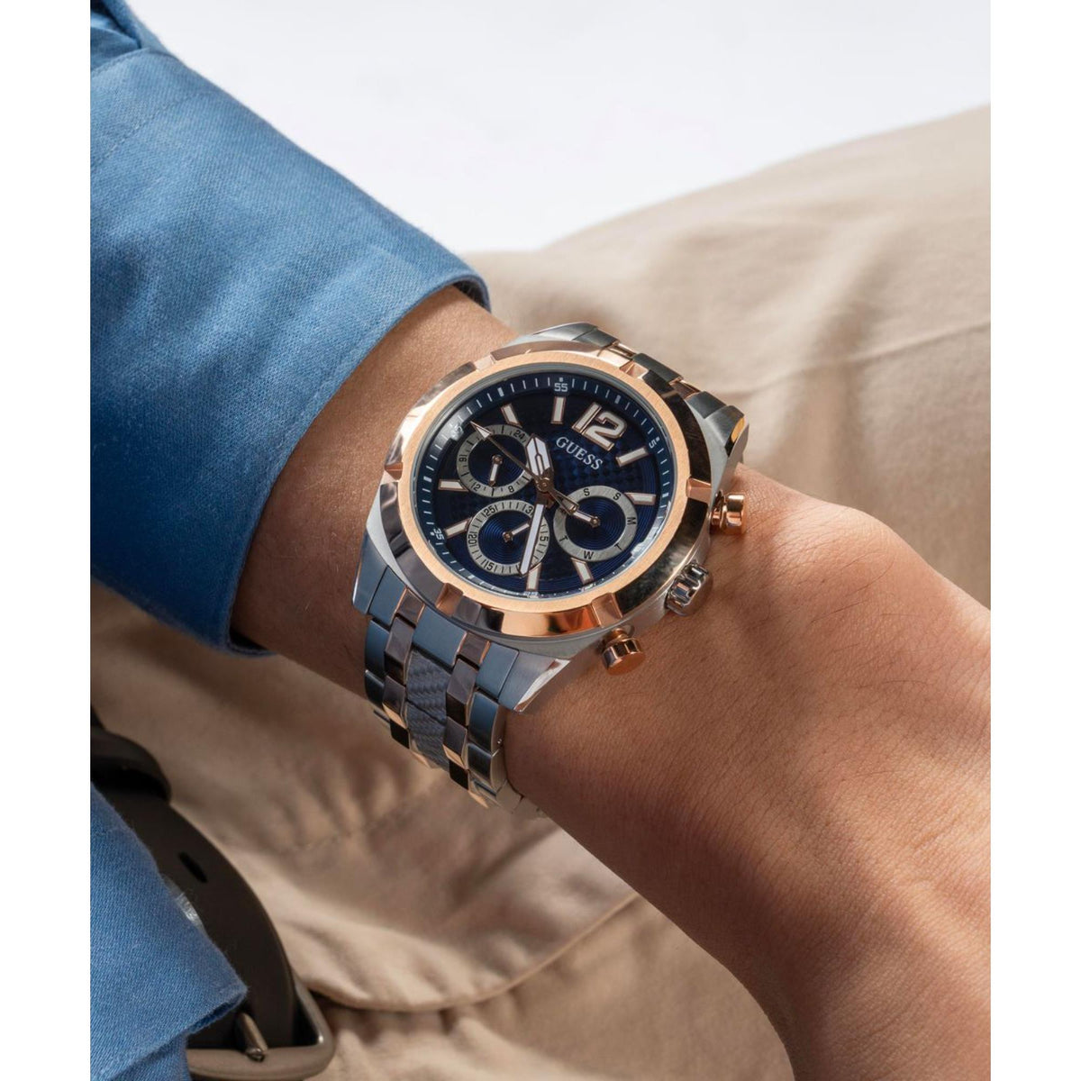 Men's stainless steel watch with blue dial and rose-gold bezel, two-tone bracelet on wrist.