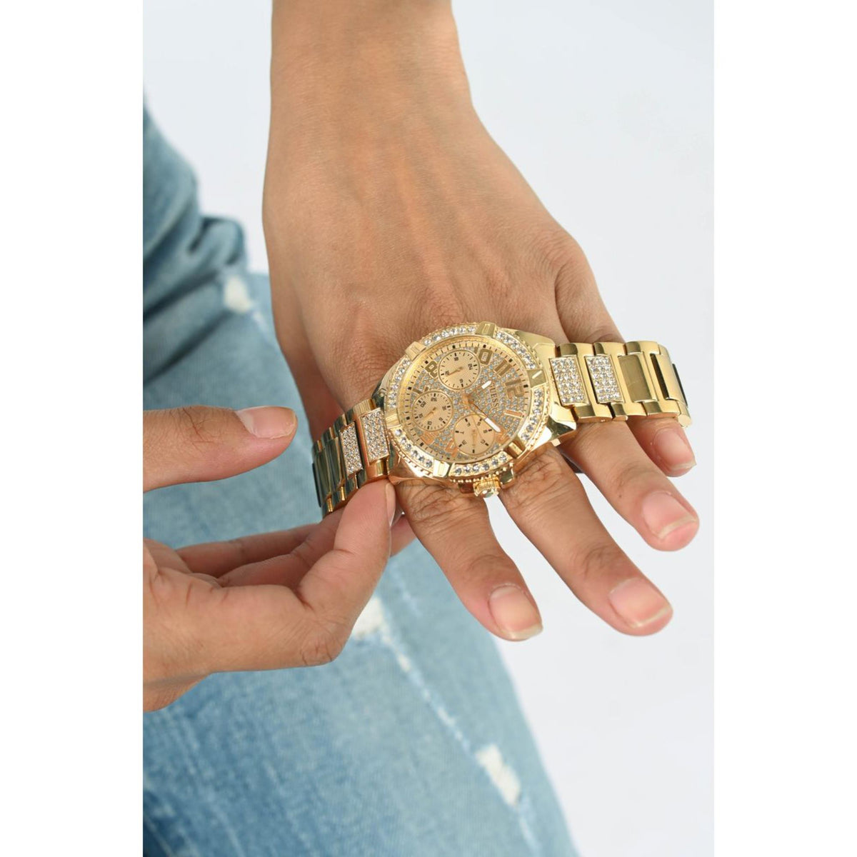 Gold women's watch with crystal bezel on wrist, champagne dial and link bracelet.