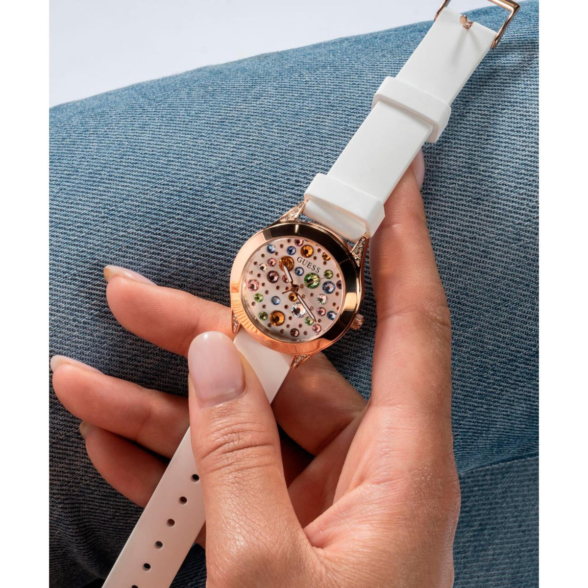 Women's watch held in hand: white silicone band with perforations, rose gold dial