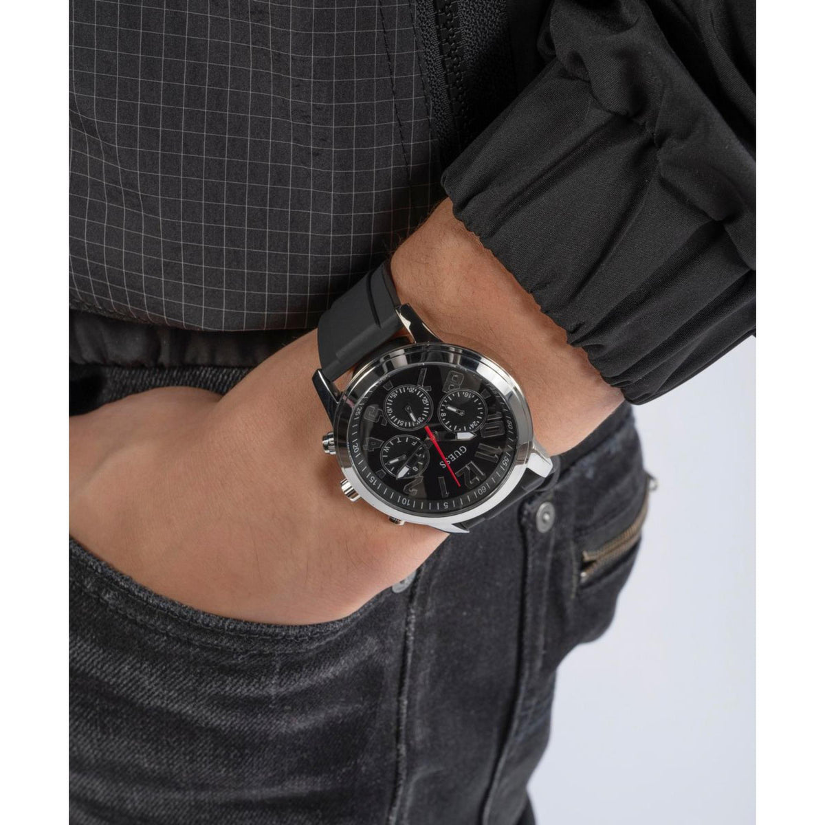 Men's black dial watch with black silicone strap on wrist, chronograph subdials visible