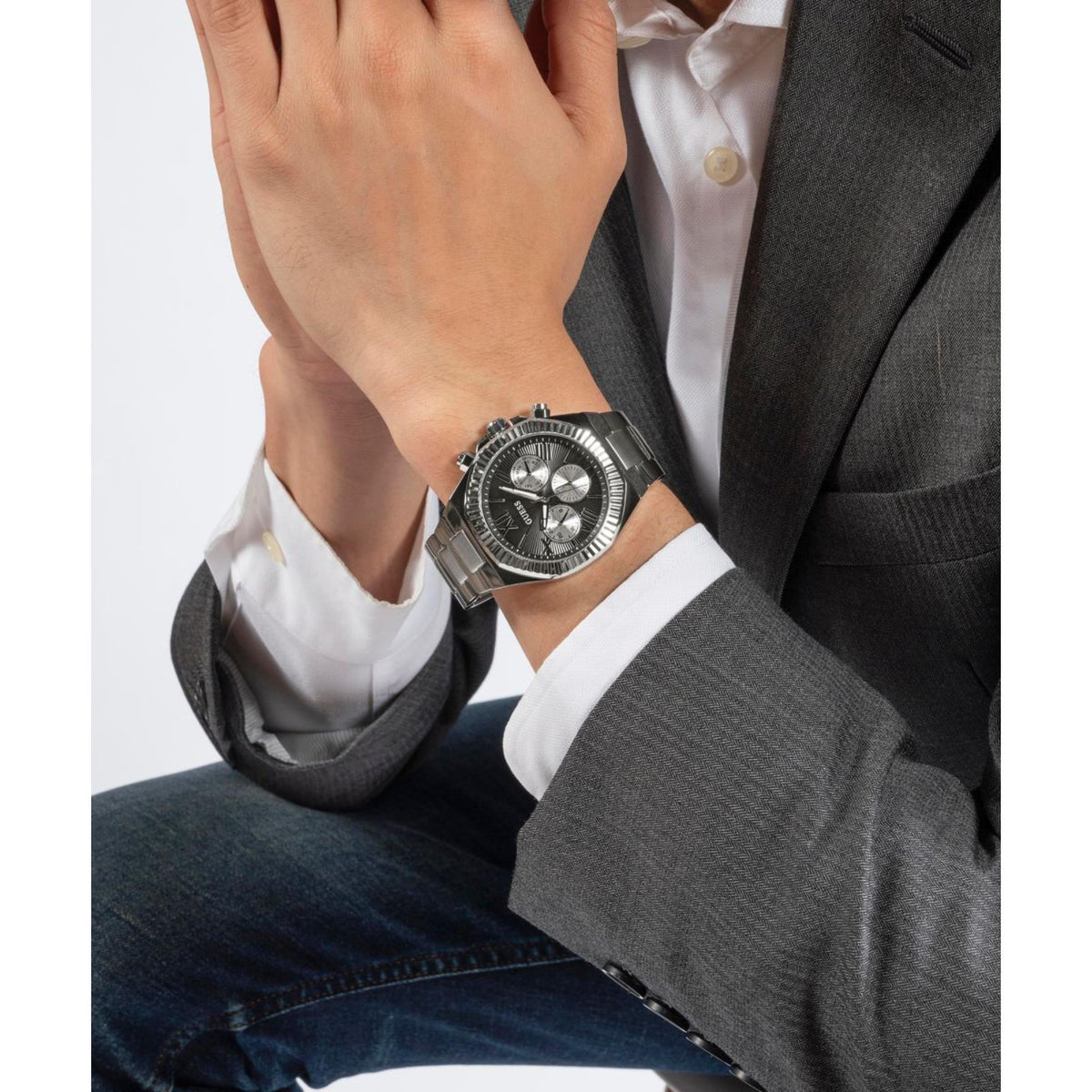Men's wristwatch worn on wrist, silver steel bracelet and black multifunction dial.