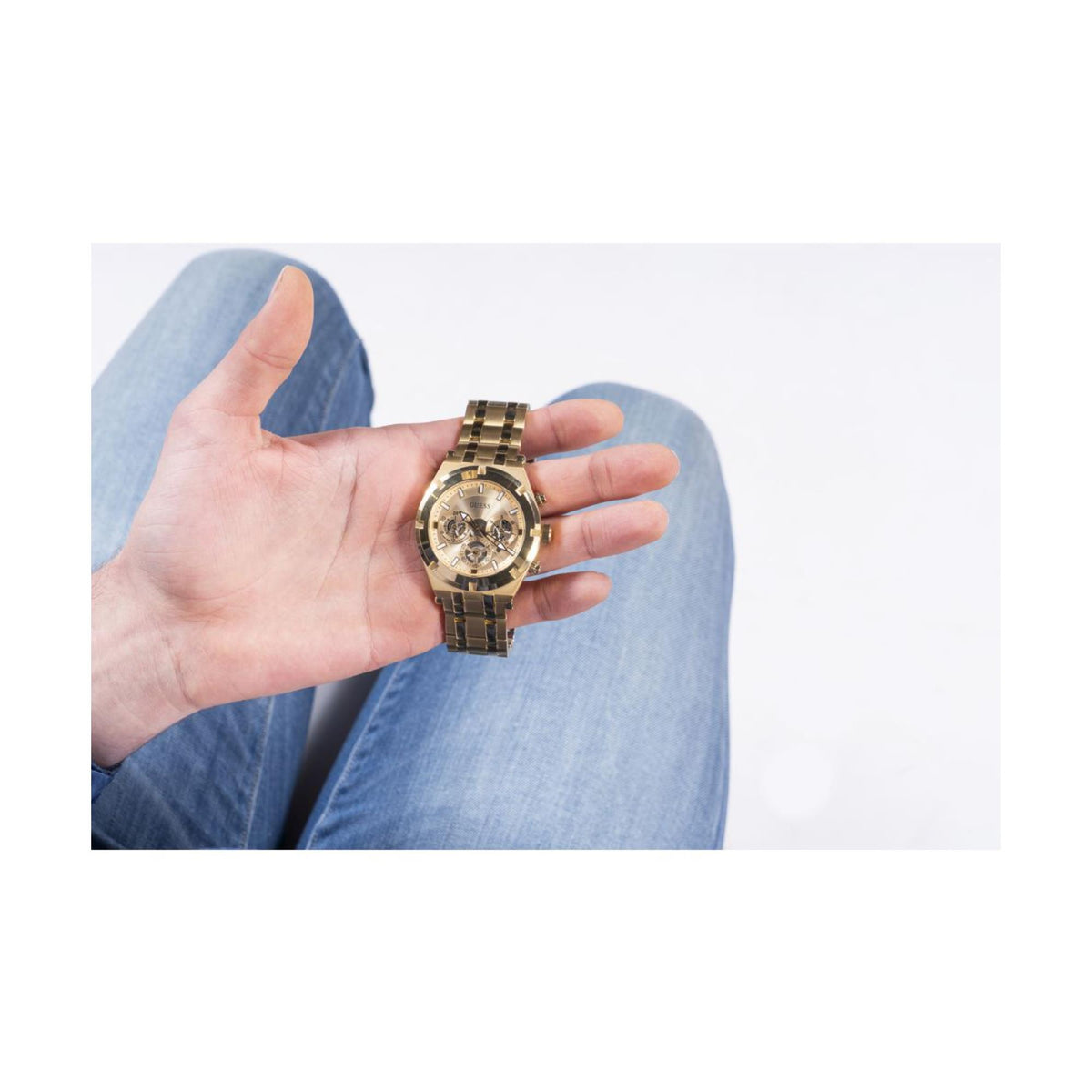 Gold-tone men’s watch held in open hand, round skeleton dial with gold-tone strap.