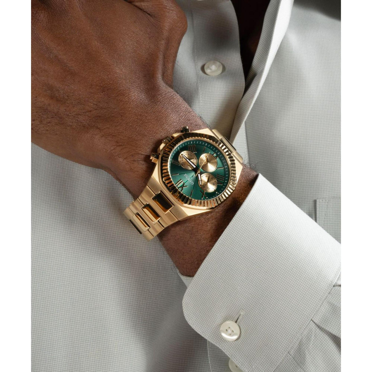 Men's gold-tone stainless steel watch with green dial on wrist, visible gold bezel