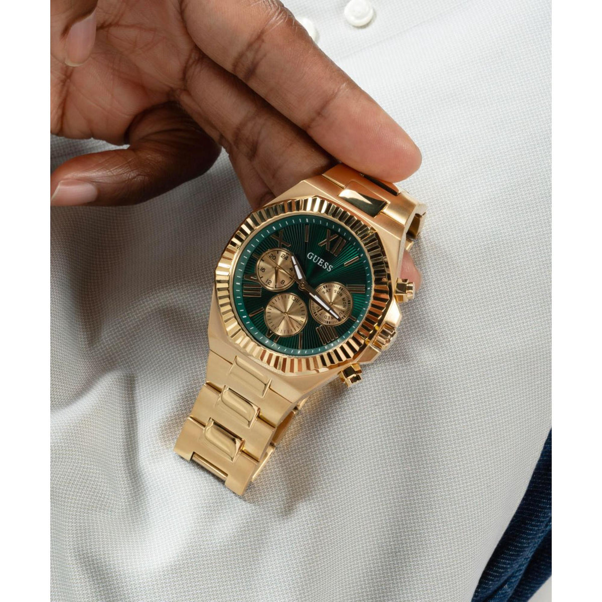 Men's gold-tone stainless steel watch with green dial and gold subdials, held in hand