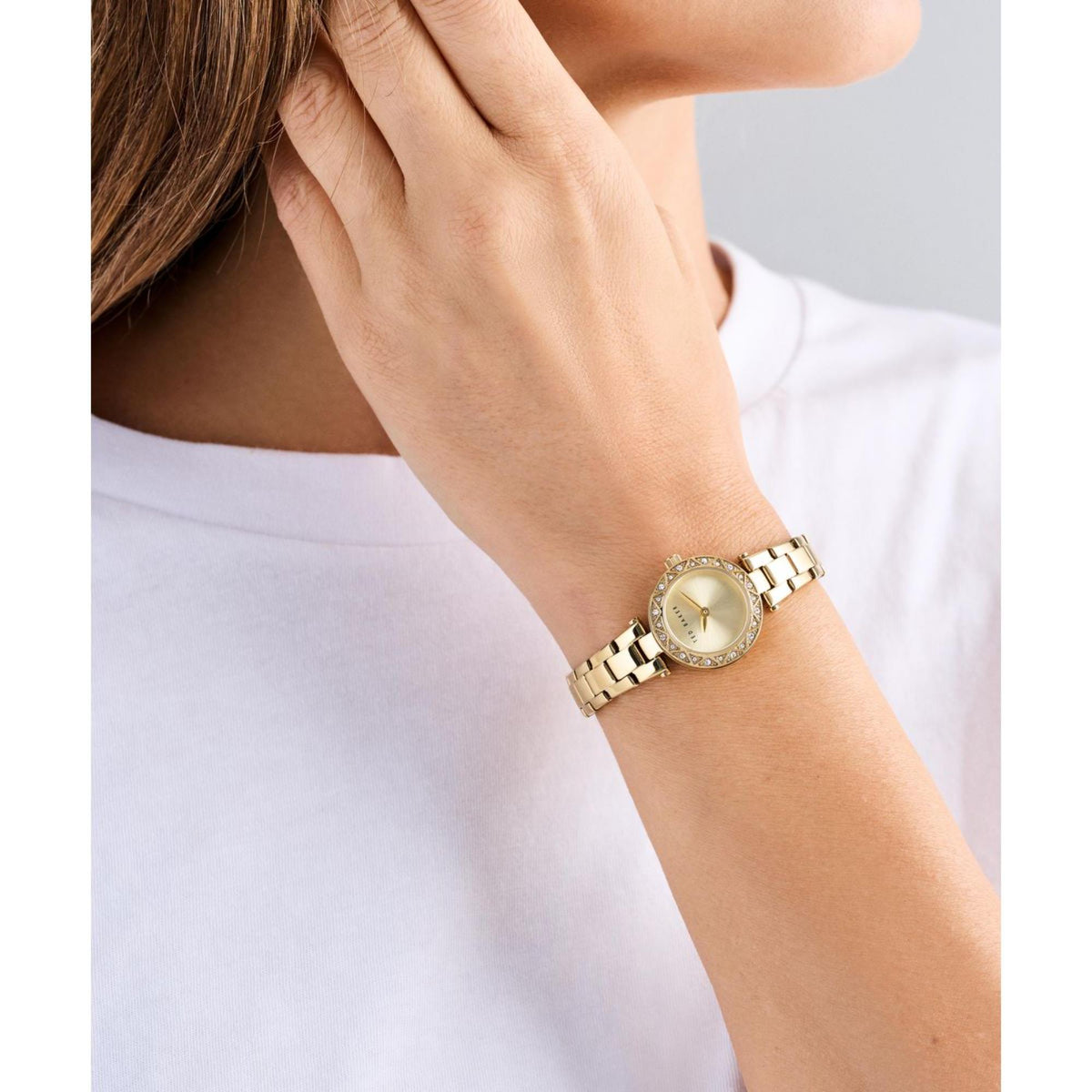 Gold-tone ladies watch with cream dial, crystal bezel on wrist and metal link strap