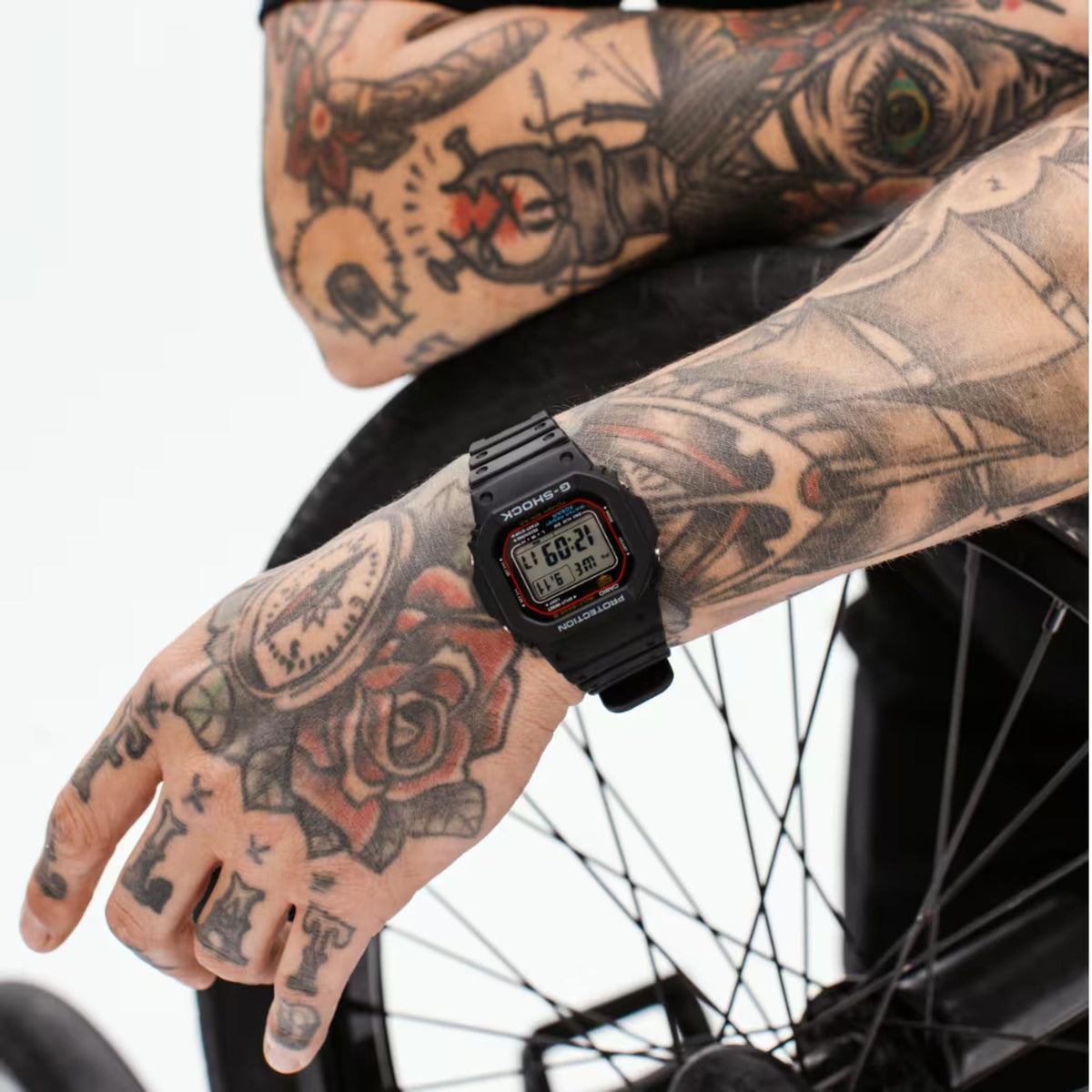 Black digital watch on a tattooed wrist, rectangular LCD with time readout