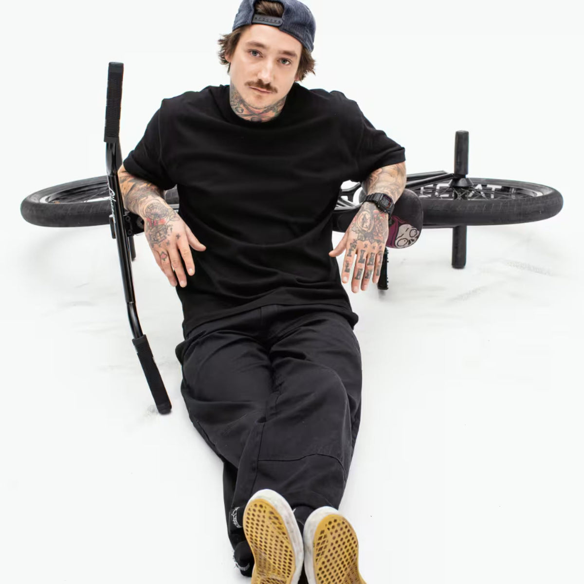 Man wearing a black digital watch on wrist while seated on a bench