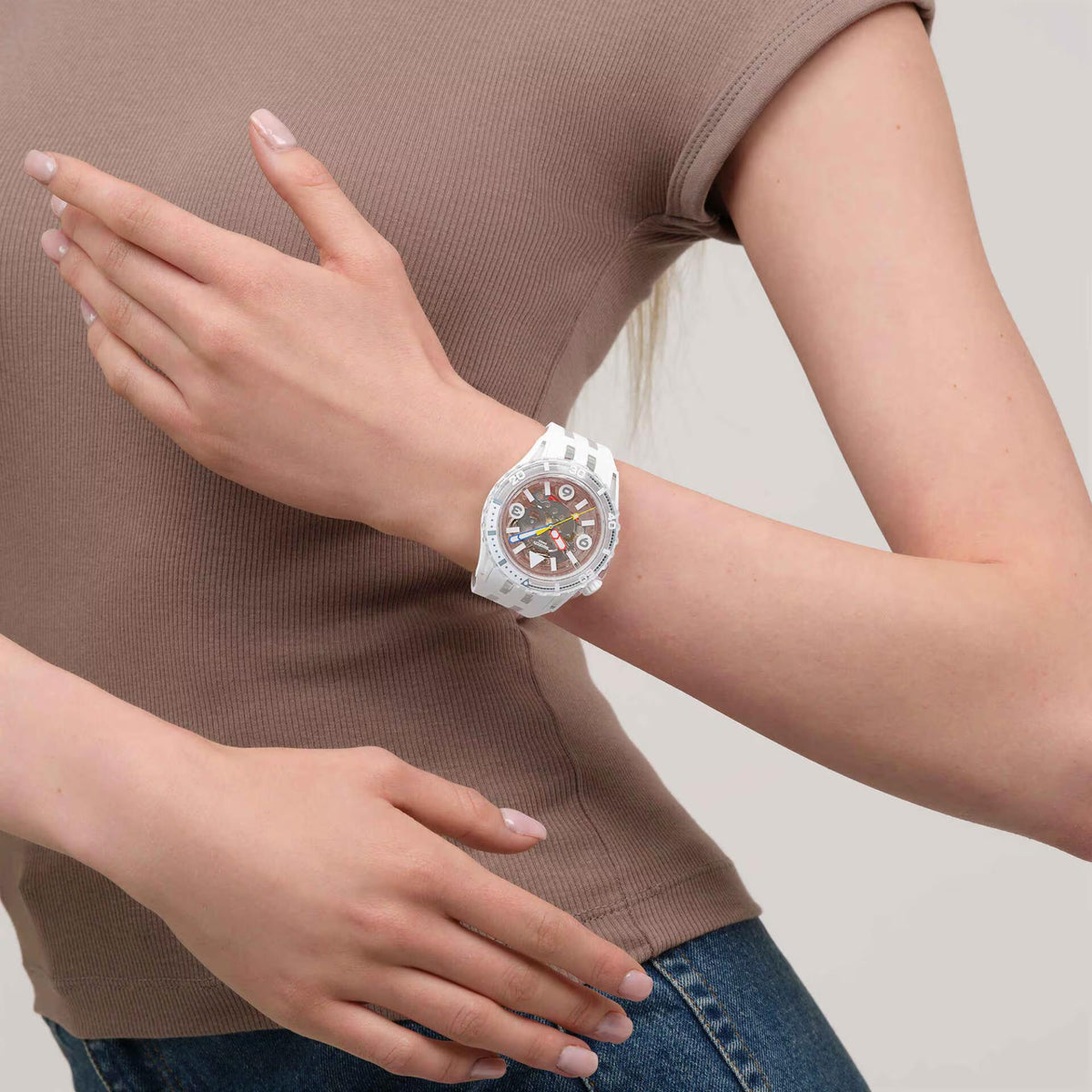 White Swatch watch on wrist, white silicone band and colored skeleton dial hands