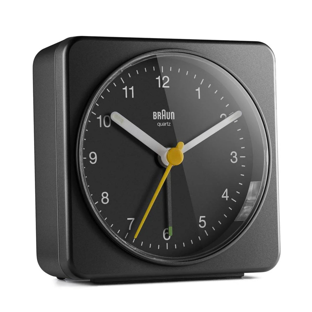 Black Braun quartz alarm clock close-up with yellow hands and white numerals on dial