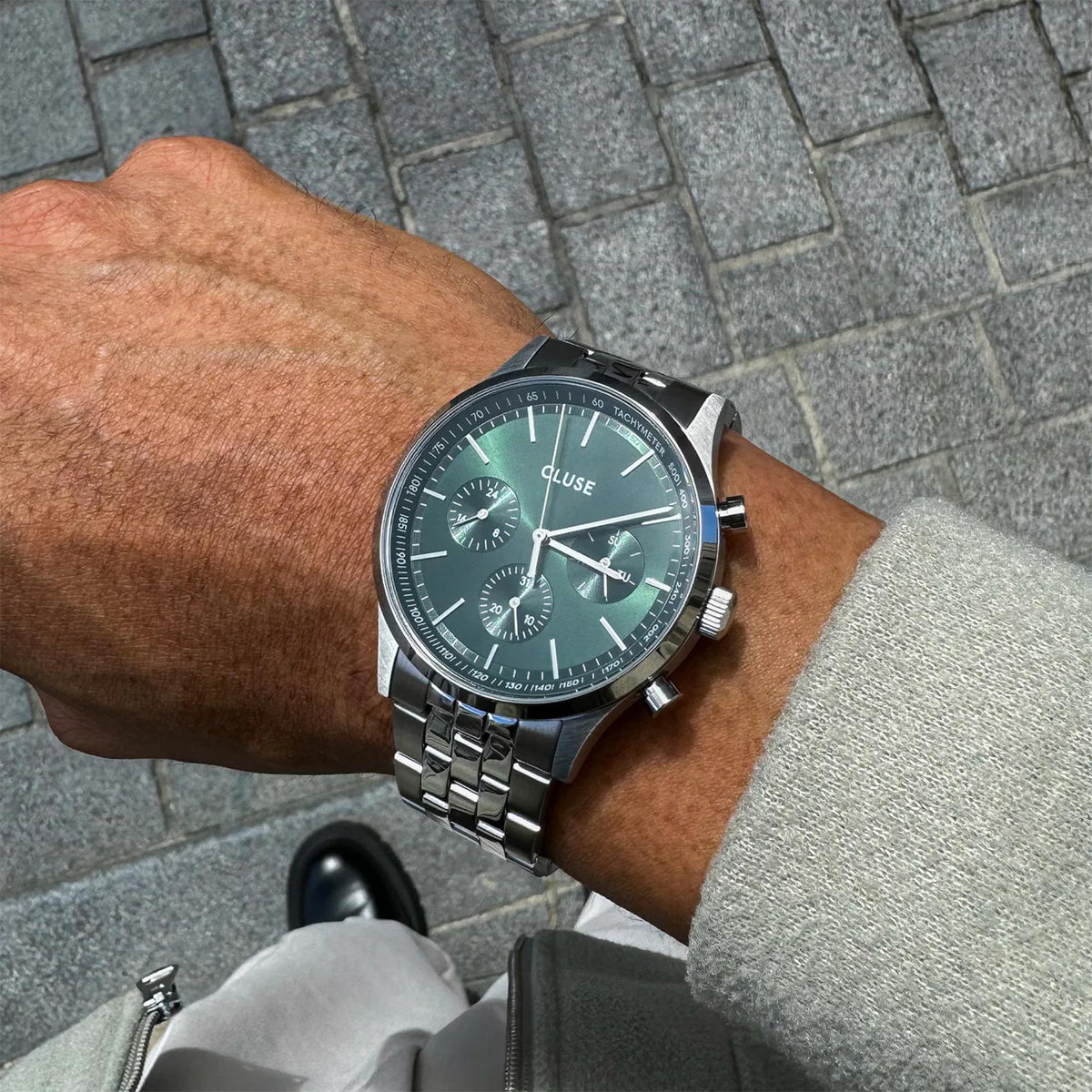 Men's wristwatch with green dial and stainless steel bracelet on arm