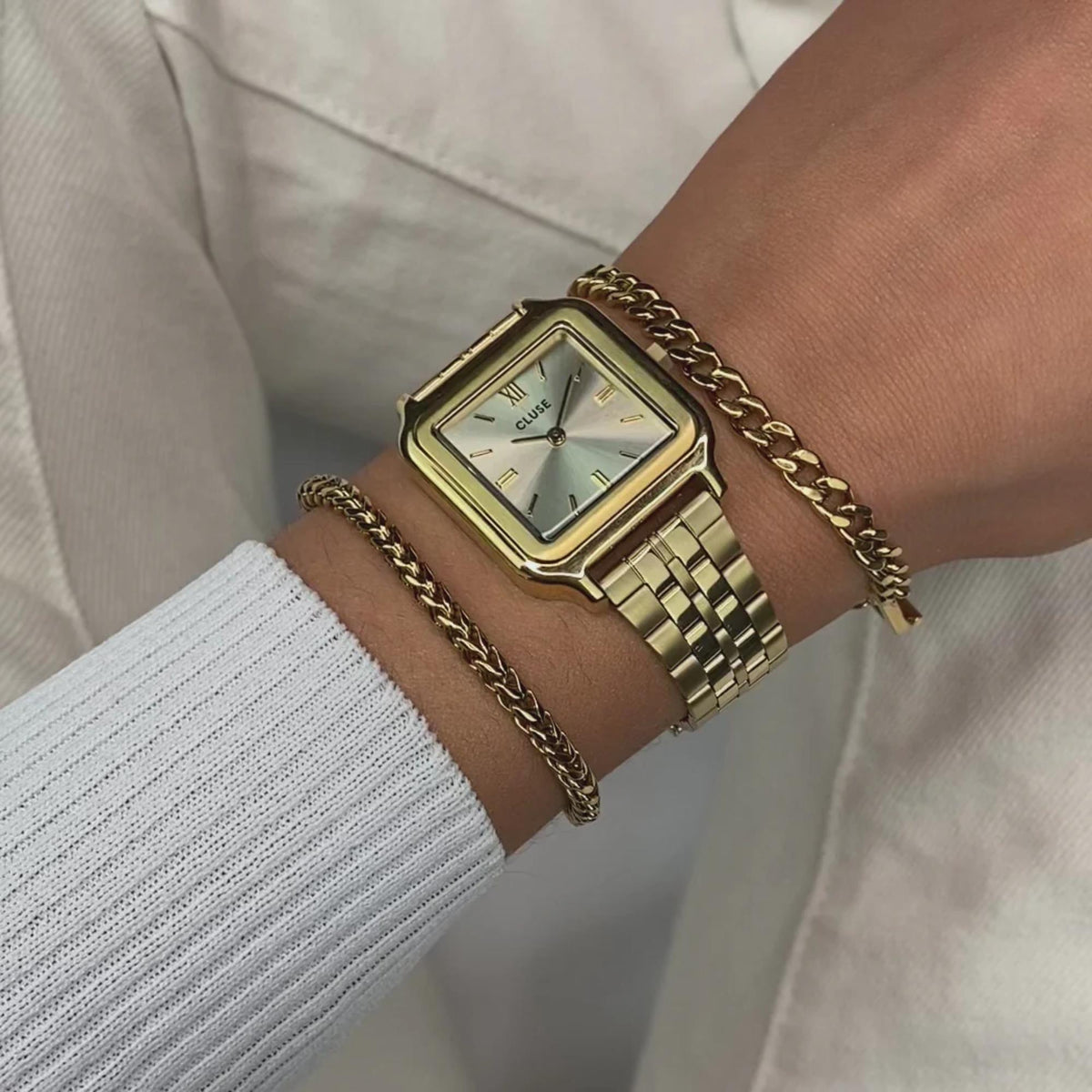 Women's gold-tone square quartz watch on wrist with metal link bracelet