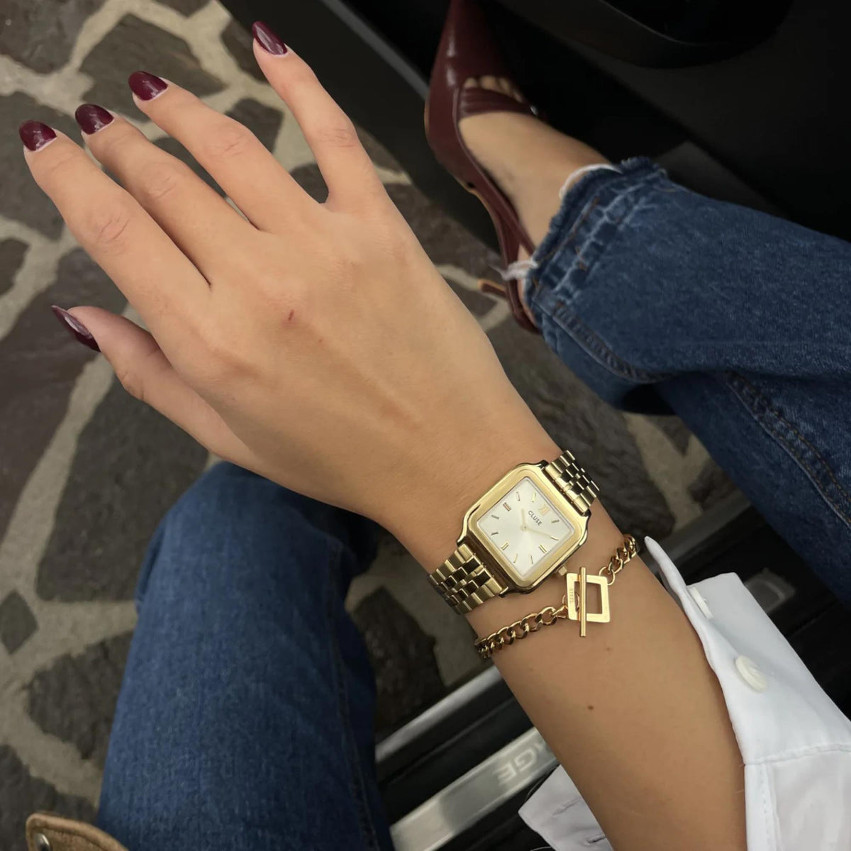 Women's gold-tone square quartz watch on wrist with metal link bracelet