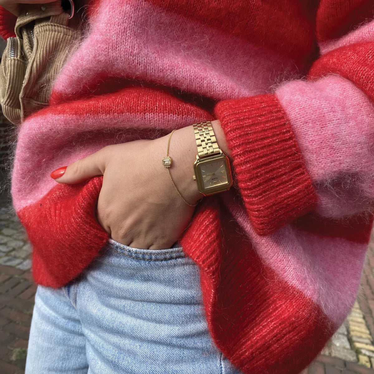 Women's gold-tone square quartz watch with metal link bracelet on sweater sleeve
