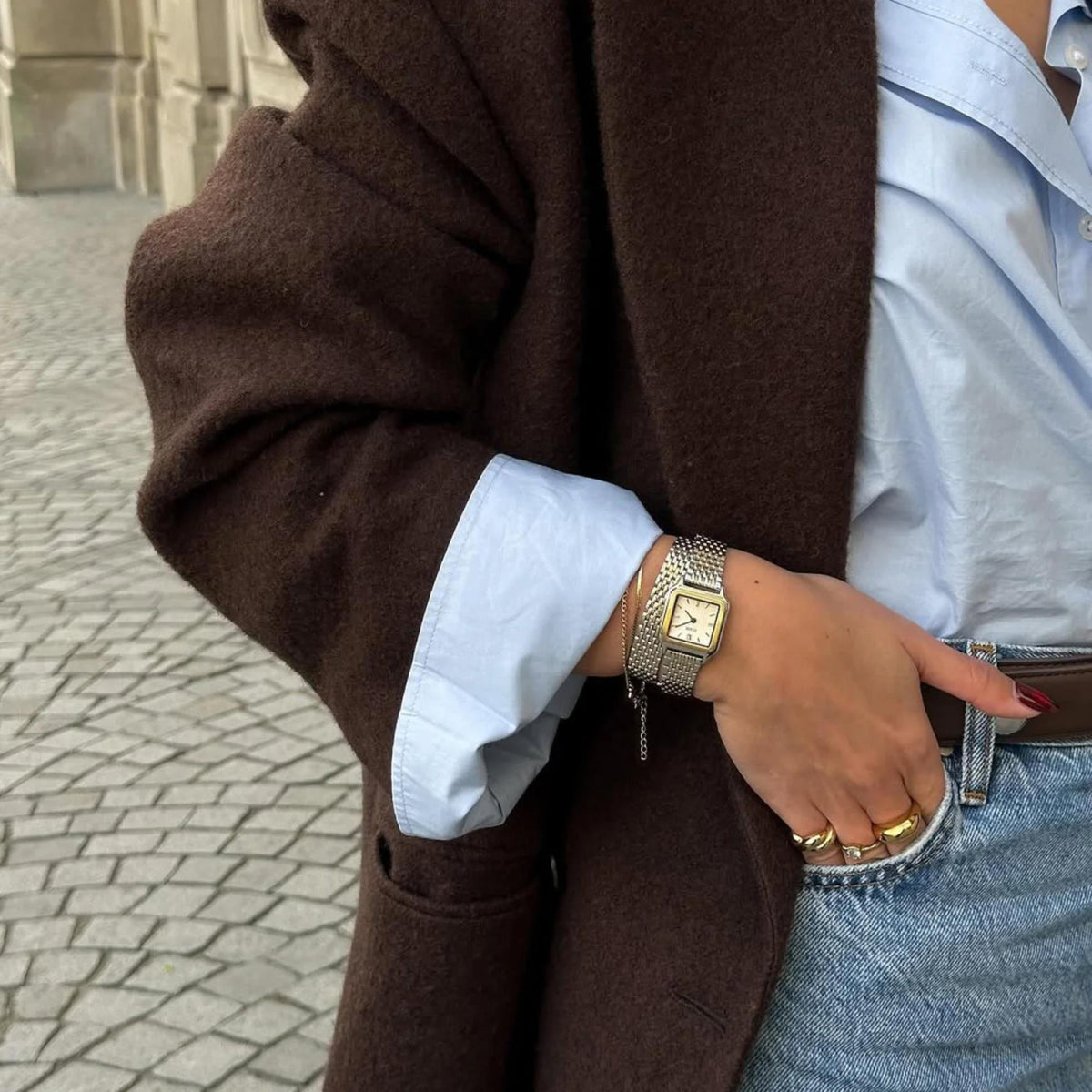 Two-tone mesh watch on wrist with square dial and gold bezel