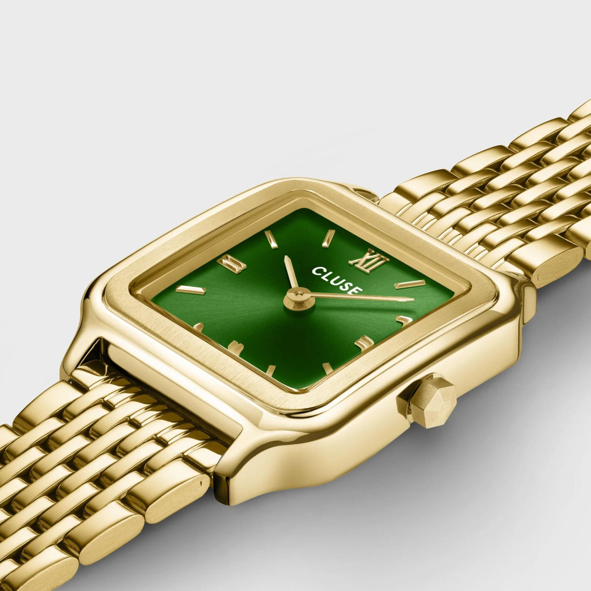 Gold-tone square watch case with green dial and metal mesh strap close-up